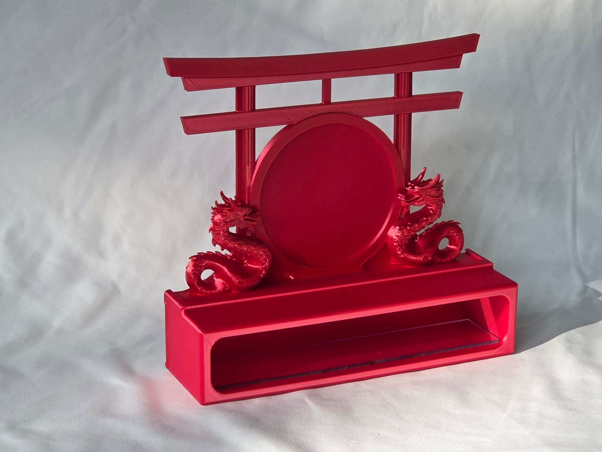 Red decorative topper with dragon design and torii gate on a white background