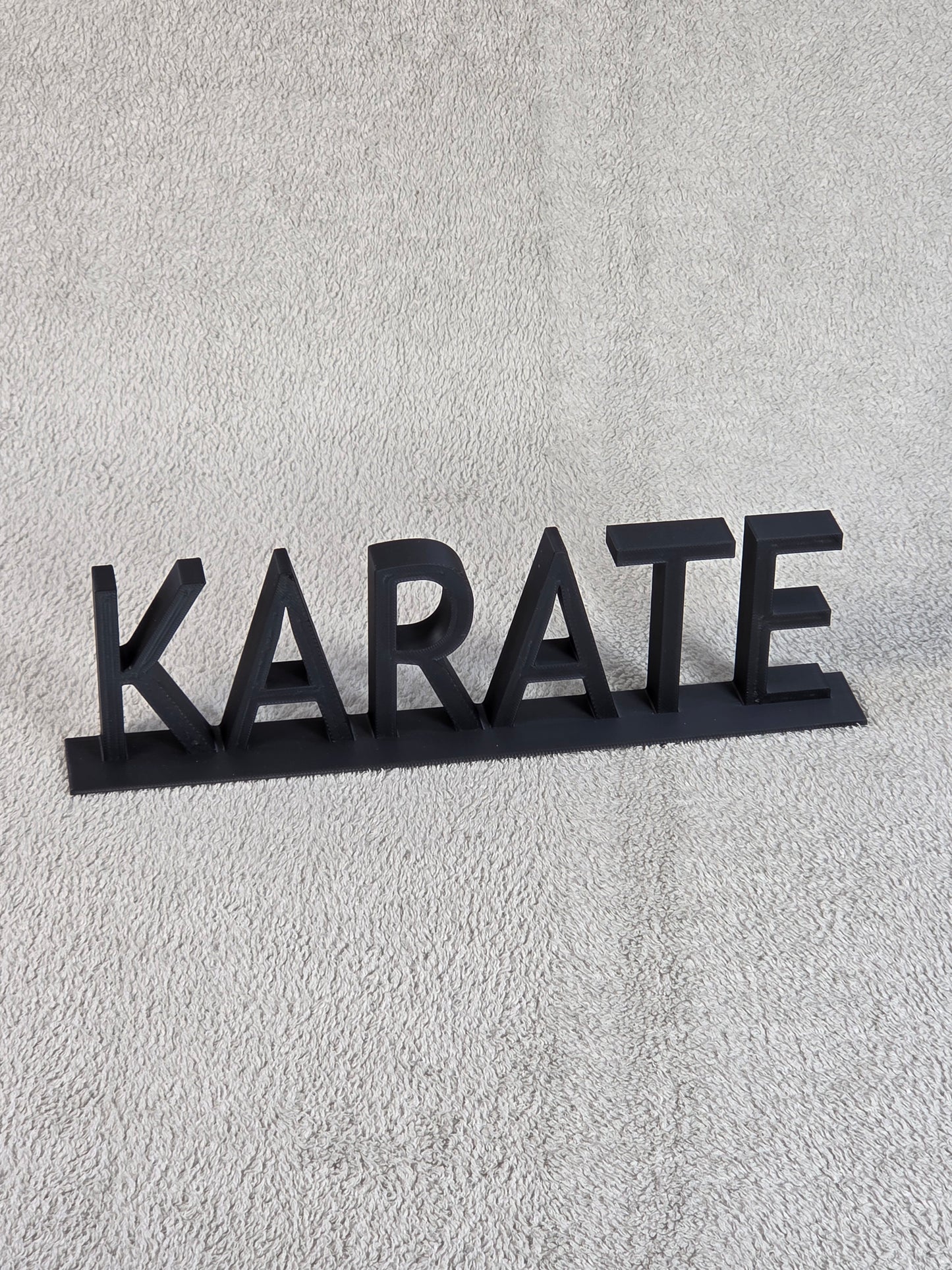 Black 'KARATE' sign on a textured gray background