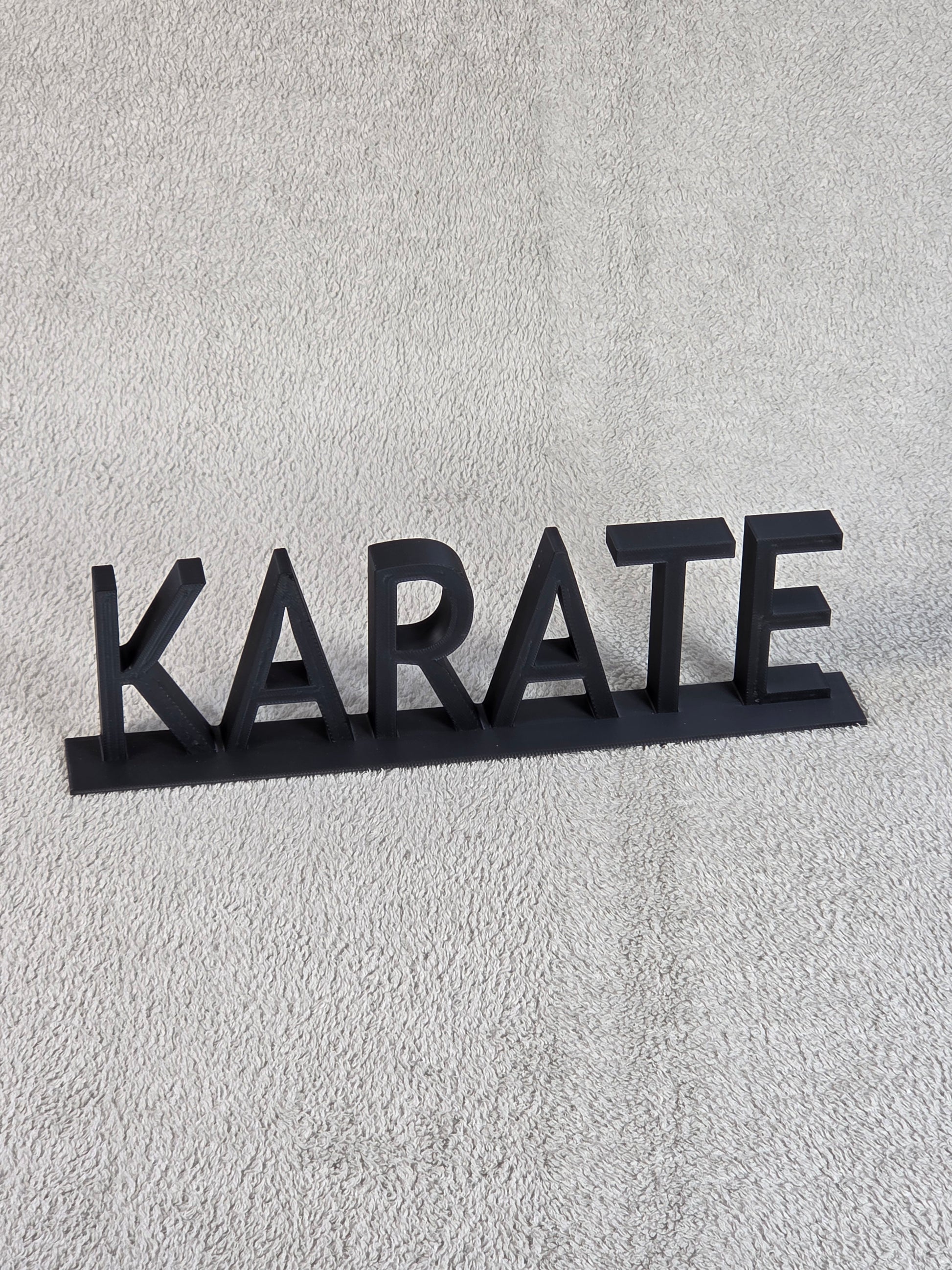 Black 'KARATE' sign on a textured gray background
