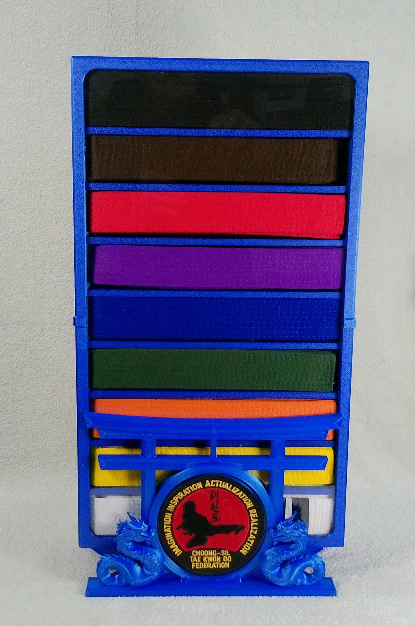 Royal Blue decorative desktop display case base with dual dragons facing each other next to a round patch area in front of a torii gate on a light gray background. Holding an 9-belt karate case with all belts displayed. A 'Karate' Topper displayed on top of case